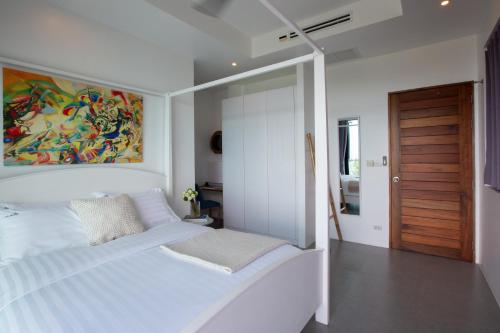 ein Schlafzimmer mit einem weißen Bett und einem Gemälde an der Wand in der Unterkunft Villa La Moon Chaweng Noi 4BR in Koh Samui 