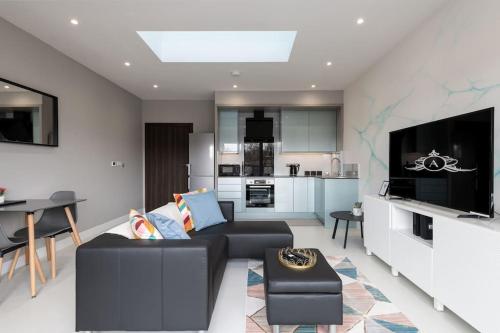a living room with a black couch and a kitchen at Thames Crossing contractor work stay - Apartment 10 in Gillingham