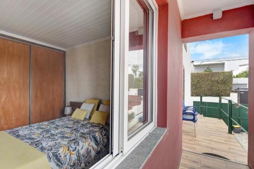 a balcony with a bed in a room with a window at Alojamento do Rosário in Lagoa