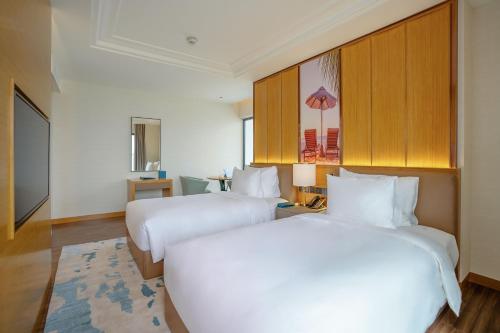 two beds in a hotel room with white sheets at Grand Hyams Hotel - Quy Nhon Beach in Quy Nhon