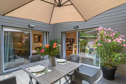 einen Tisch mit Stühlen und einem Sonnenschirm auf einer Terrasse in der Unterkunft Au coeur des Bambous - Charmant appt au calme avec terrasse in Vannes