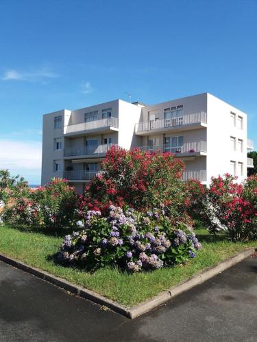 - un grand immeuble avec des fleurs devant dans l'établissement Appartement 113m2, vue spectaculaire sur océan et monts d'Espagne, à Biarritz
