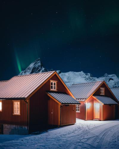 two barns in the snow with the northern lights at Reinefjorden Sjøhus in Reine