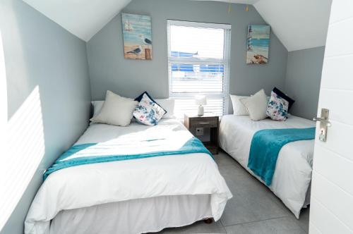 two beds in a room with blue walls at Starfish Cottage, Langebaan in Langebaan