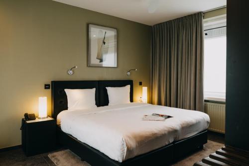 a bedroom with a bed with two lamps and a window at Hotel Astoria Gent in Ghent