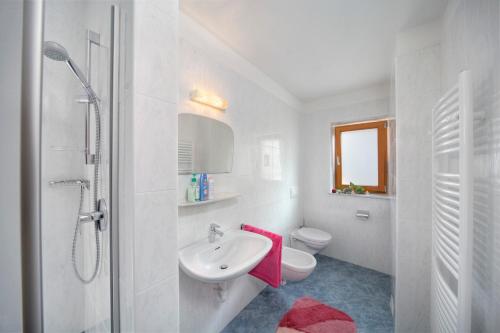 a white bathroom with a sink and a toilet at Oberhuberhof in Rodengo