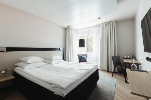 a bedroom with a large white bed and a desk at Home Hotel Jugend in Helsinki
