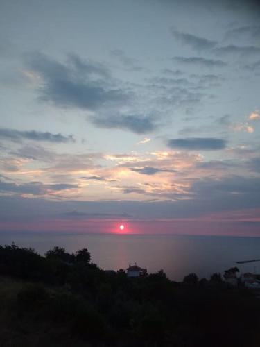 a sunset over the water with the sun in the sky at Villa Nestor in Platamonas