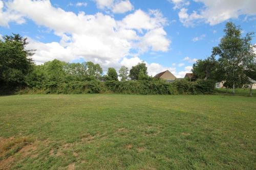 a large grass field with trees and a blue sky at Gîte de Savenay in Aunay-en-Bazois