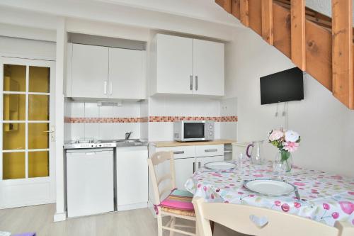une cuisine avec une table et des chaises et une cuisine avec des armoires blanches dans l'établissement Le Sillon - Appartement proche de la plage, à Saint-Malo