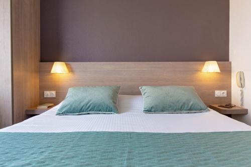 a bedroom with a large bed with blue pillows at Best Western Plus La Marina in Saint-Raphaël