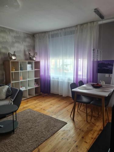 ein Wohnzimmer mit Esstisch und lila Vorhängen in der Unterkunft Jüri 43c - Margus rentals in Võru