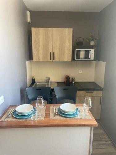 eine Küche mit einem Tisch mit Tellern und Weingläsern in der Unterkunft Appartement style hôtel cocooning in Limoges