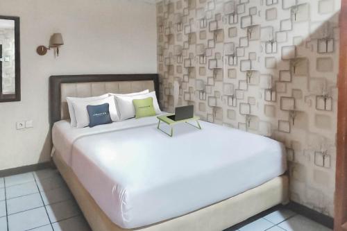 a bedroom with a white bed with a laptop on it at Hotel Syariah Citra Nusantara Balikpapan in Klandasan Kecil