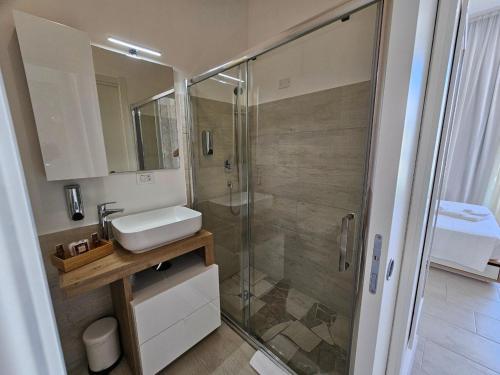 bagno con doccia in vetro e lavandino di Luxury Pool Suites - Città Bianca a Pescara