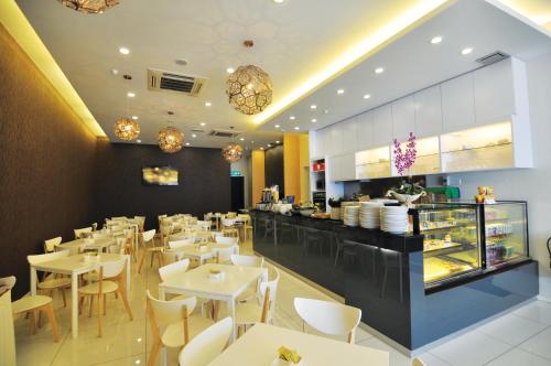 a restaurant with white tables and chairs and a counter at MIO BOUTIQUE Hotel in Melaka