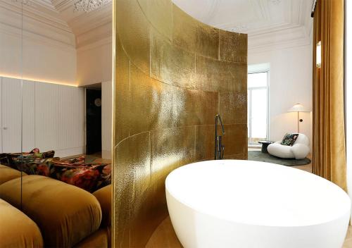 a bathroom with a tub and a gold wall at Montebelo Vista Alegre Lisboa Chiado Hotel in Lisbon