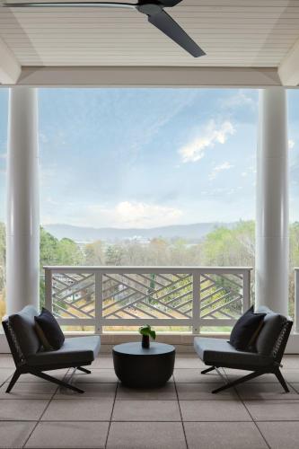 a patio with two chairs and a table and a balcony at Kimpton - The Forum Hotel by IHG in Charlottesville