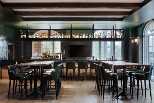 a bar with tables and chairs in a room with windows at Kimpton - The Forum Hotel by IHG in Charlottesville