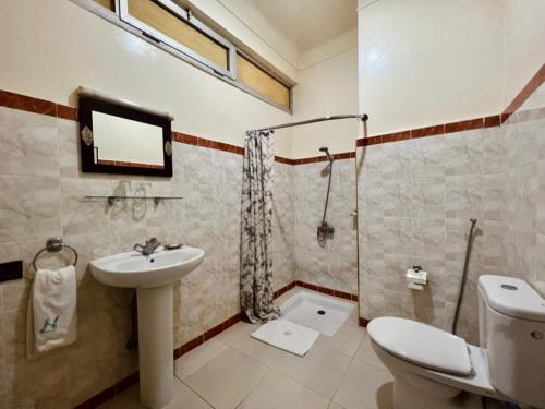 y baño con aseo, lavabo y ducha. en Hôtel Narjisse en Marrakech