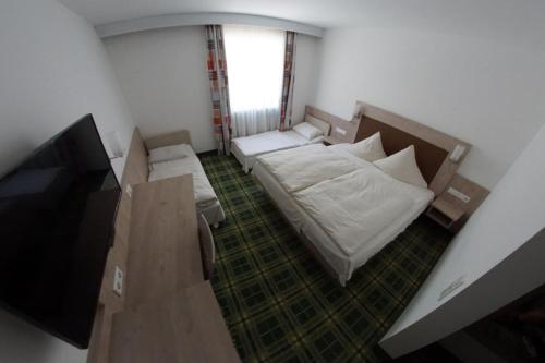 a small room with two beds and a television at Gasthof zum Bayerischen in Greding