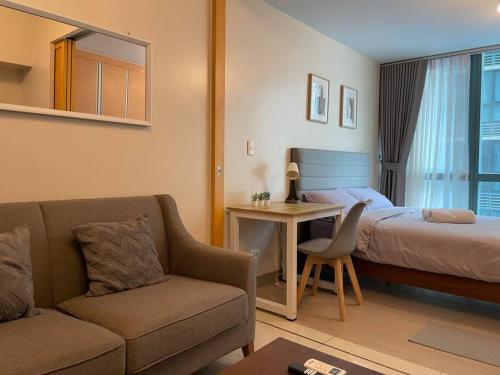 a hotel room with a bed and a couch and a desk at Cozy 1 BR One Uptown Residences BGC in Manila