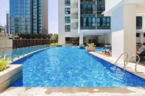 une grande piscine au milieu d'un bâtiment dans l'établissement Cozy 1 BR One Uptown Residences BGC, à Manille