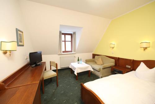ein Hotelzimmer mit einem Bett, einem TV und einem Sofa in der Unterkunft Gasthof zum Bayerischen in Greding