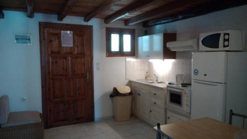 a kitchen with a wooden door and a white refrigerator at Amaranthos Skiathos View in Megali Ammos