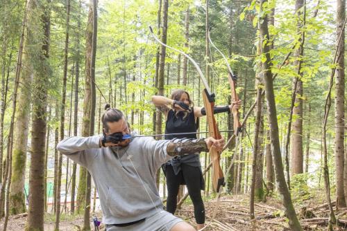 a man and woman in the woods with a bow and arrow at Narzissendorf Zloam Apartments in Grundlsee