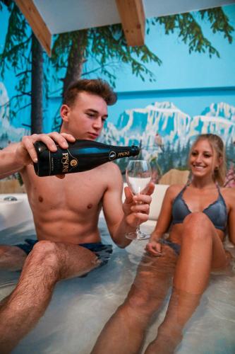 a man pouring a glass of wine in a swimming pool at Wellness Hotel Lupo Bianco in Canazei