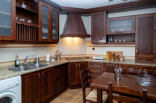 a kitchen with wooden cabinets and a table and a sink at Los olivares de Rober in Polán