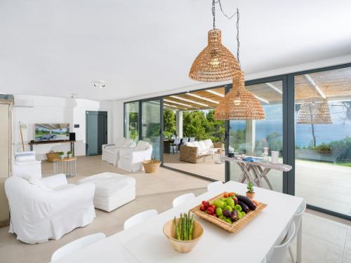 ein Wohnzimmer mit weißen Möbeln und einem Tisch mit einer Obstschale in der Unterkunft Dilean luxury villa in Vourvourou