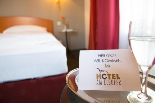 a table with a wine glass and a sign on it at Hotel AM ELBUFER in Hamburg