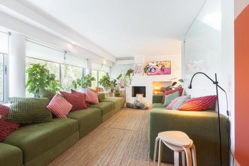uma sala de estar com sofás verdes e almofadas vermelhas em Beach Villa - 16min to Downtown - 30 PPL em Paço de Arcos
