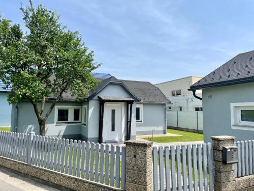 a white fence in front of a white house at sHome TinyHouse Feldkirchen bei Graz - Self-Check-in in Feldkirchen bei Graz