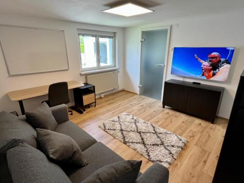 uma sala de estar com um sofá e uma televisão de ecrã plano em sHome TinyHouse Feldkirchen bei Graz - Self-Check-in em Feldkirchen bei Graz