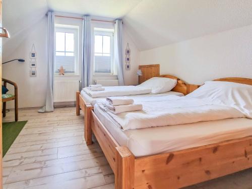 two beds in a room with two windows at Am Sommerdeich in Norden