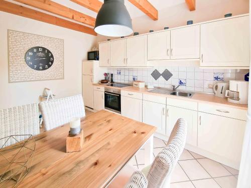 a kitchen with a wooden table and white cabinets at Am Sommerdeich in Norden