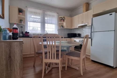 a kitchen with a table and chairs and a white refrigerator at Comfortable 3 bebrooms old home with parking in Sunshine