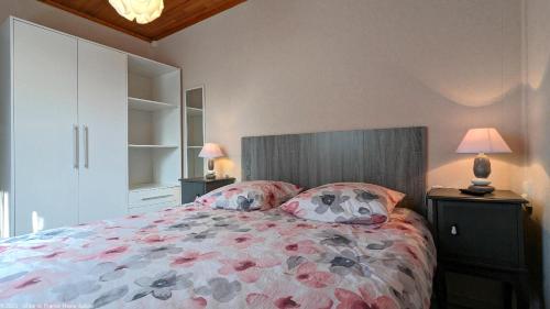 ein Schlafzimmer mit einem Bett mit Blumenbettdecke und zwei Lampen in der Unterkunft Gîte Le Saule in Pesmes