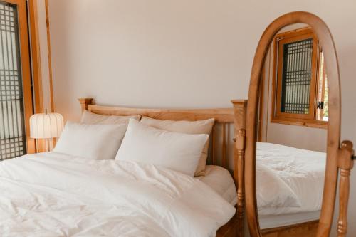 a bedroom with a mirror and a bed with white sheets at Gyeongju Hanok Sohwa in Gyeongju