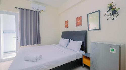 - une chambre avec un lit doté de draps blancs et une fenêtre dans l'établissement Apartment Bogorienze, à Bogor