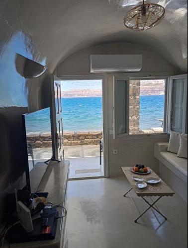 a living room with a view of the ocean at Cave of Love Seafront Sunset View Santorini in Akrotiri