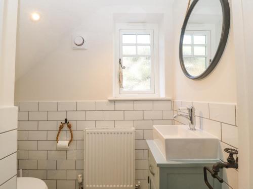 a white bathroom with a sink and a mirror at Haul A Gwynt in Criccieth