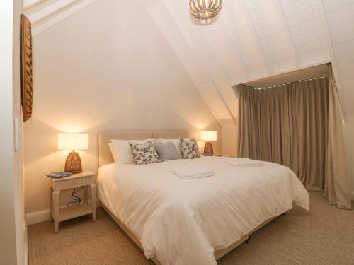 a bedroom with a large white bed and two lamps at Haul A Gwynt in Criccieth