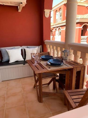 a table with plates and glasses on a balcony at Hispalis Mazagón Beach 303 in Mazagón