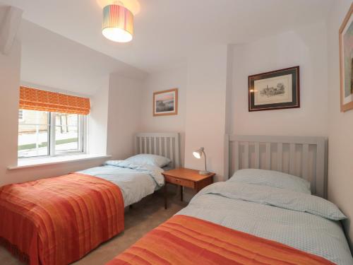 1 dormitorio con 2 camas, mesa y ventana en Holly Cottage en Yeovil