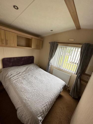 Habitación pequeña con cama y ventana en Golden Palm Resort, Sherwood Plot, Abi Windsor S214, 6 Berth en Chapel Saint Leonards