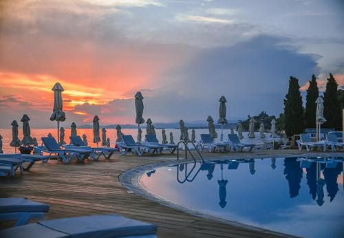 a resort with a pool and chairs and a sunset at Acrotel Lilyann Boutique Hotel in Elia
